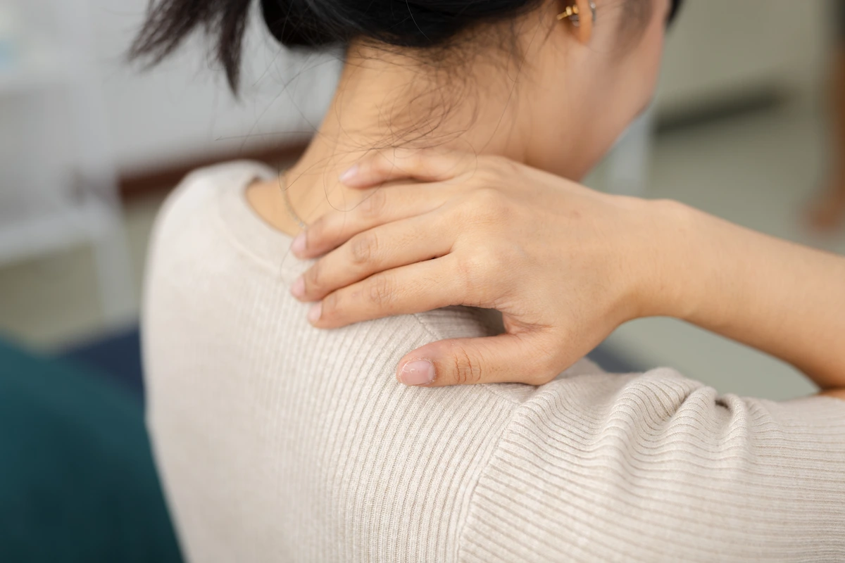 Woman placing hand on neck and shoulder